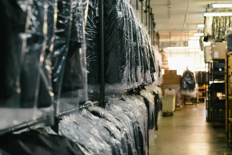 Dark suits in clear protective garment covers on a warehouse rail