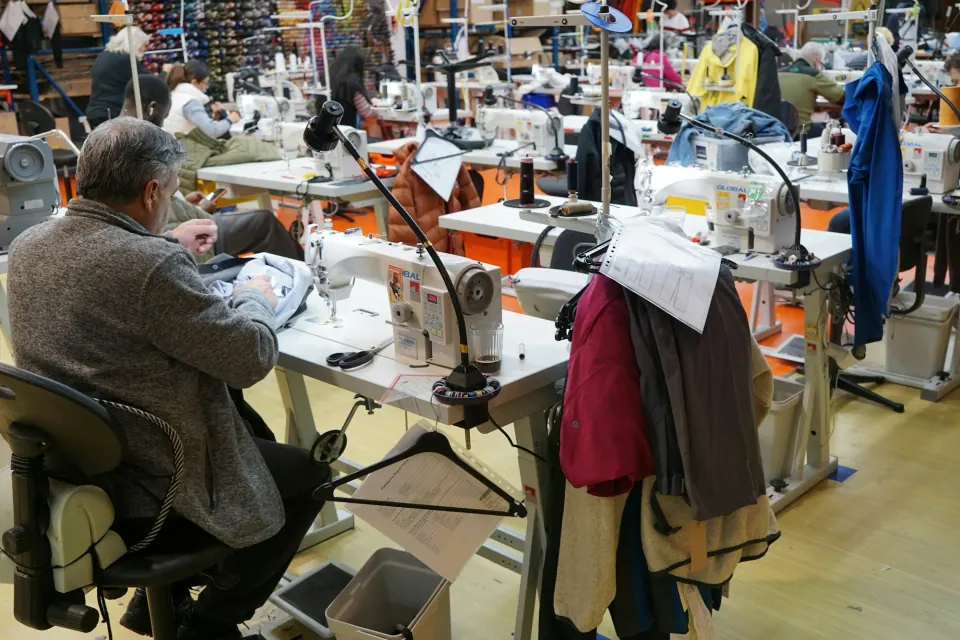 Apparel workshop floor with sewing stations, operator seen from behind