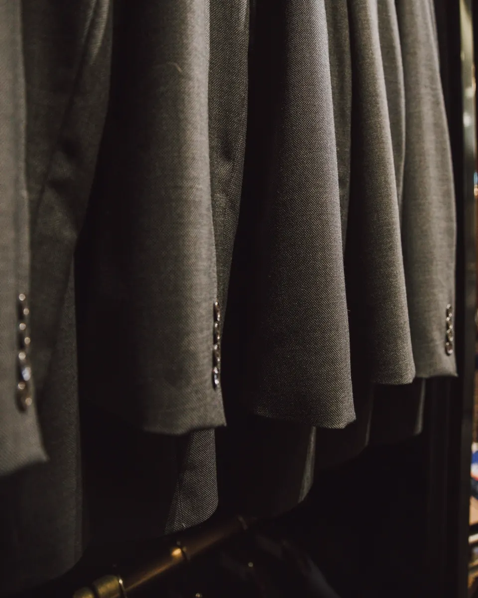 Close-up of charcoal suit jackets hanging in a row